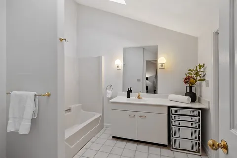 a bathroom with a tub sink and mirror
