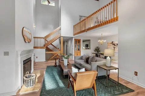 a living room with couches a rug and a dining table with wooden floor