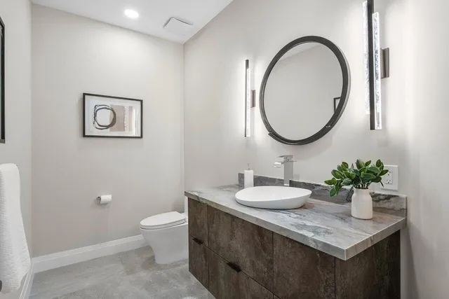 a bathroom with a granite countertop sink a toilet and a mirror