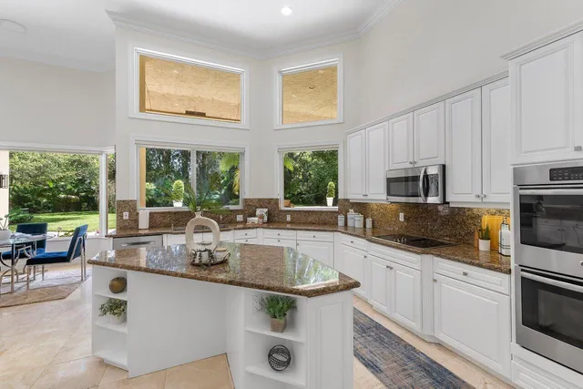 a kitchen with stainless steel appliances granite countertop a sink and a stove next to a window
