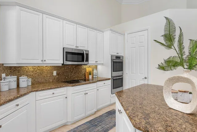 a kitchen with granite countertop white cabinets and stainless steel appliances