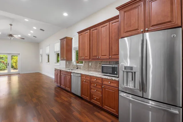 a kitchen with stainless steel appliances granite countertop a refrigerator a sink dishwasher and wooden cabinets with wooden floor