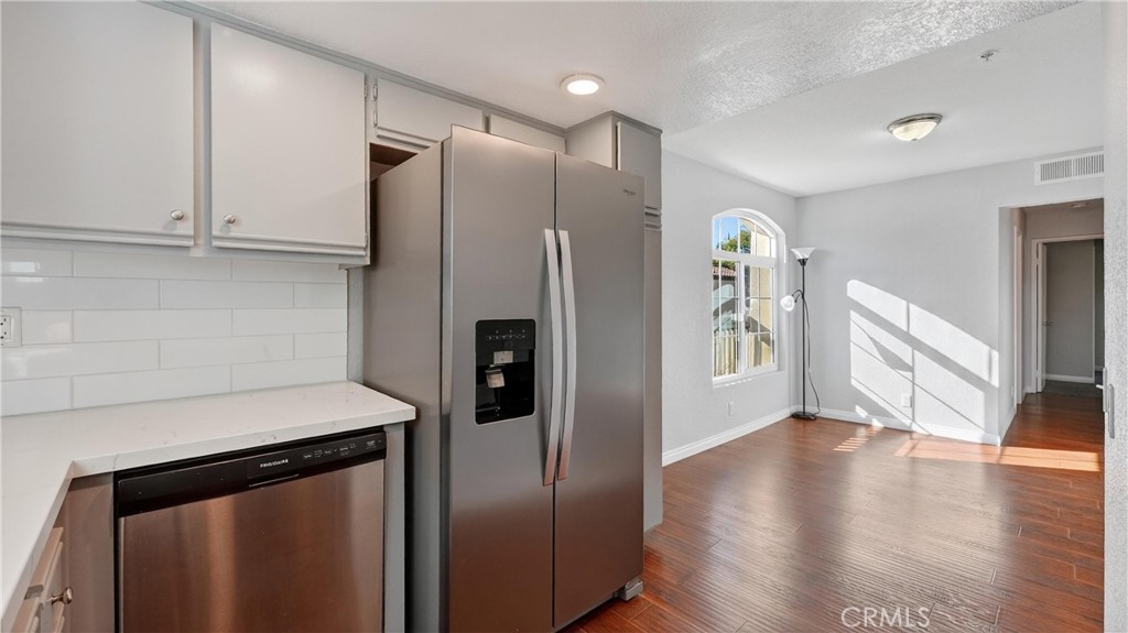 103 South Cross Creek Road, Unit B Orange, CA 92869 - Photo 8 of 29 a kitchen with stainless steel appliances granite countertop a refrigerator a sink and white cabinets with wooden floor
