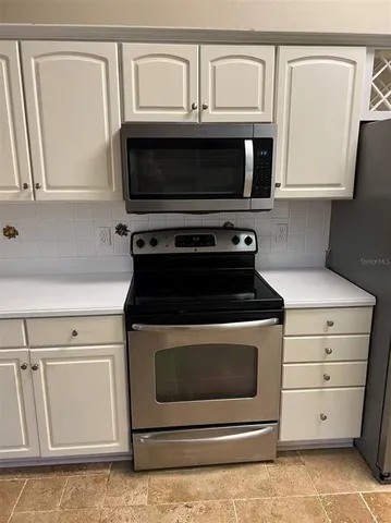 a kitchen with white cabinets and sink