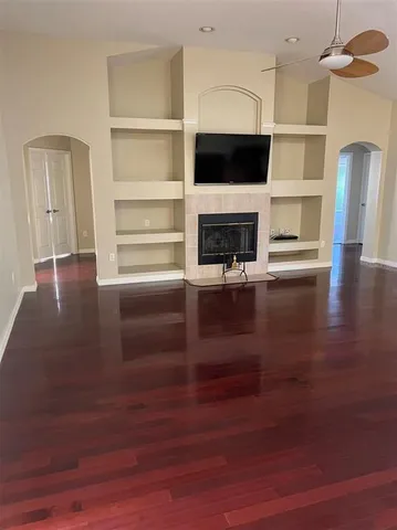 a view of a livingroom with wooden floor a ceiling fan and windows