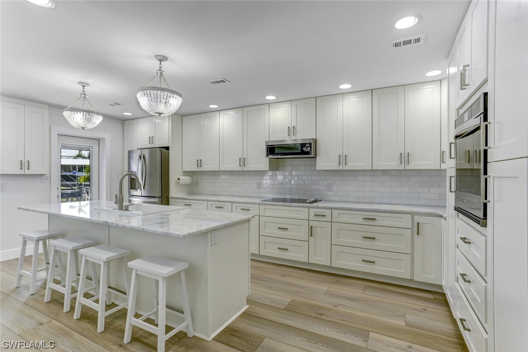 a large kitchen with granite countertop lots of white cabinets stainless steel appliances and a sink
