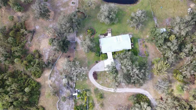an aerial view of a house with a yard and large trees