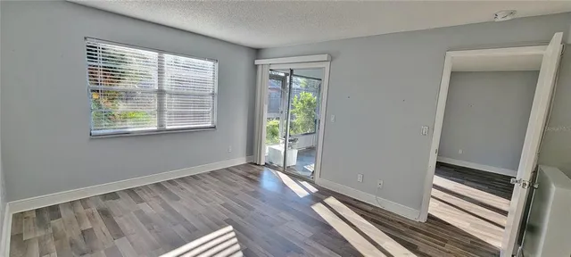 a view of an empty room with wooden floor and a window