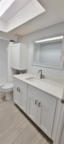 a spacious bathroom with a double vanity sink a toilet and a mirror