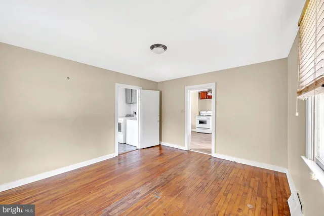 a view of empty room with wooden floor and window