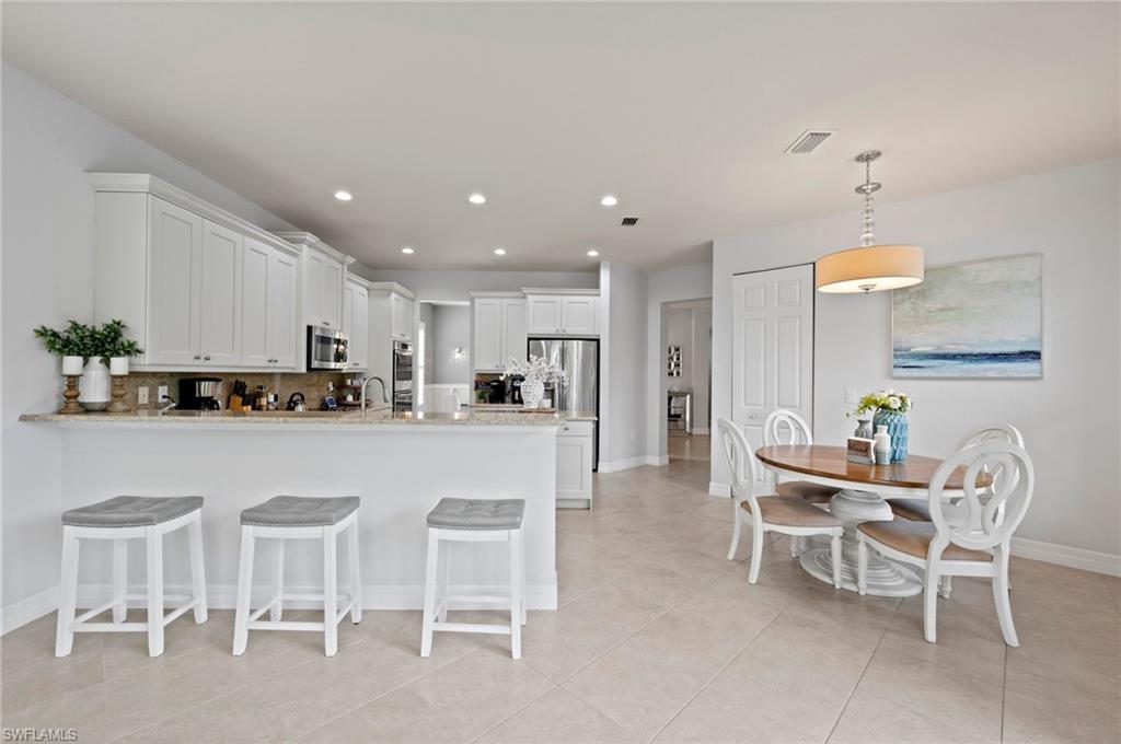 3082 Hudson Terrace Naples, FL 34119 - Photo 16 of 48 a kitchen with a dining table chairs and white cabinets