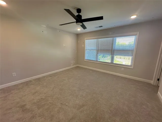 an empty room with ceiling fan and windows
