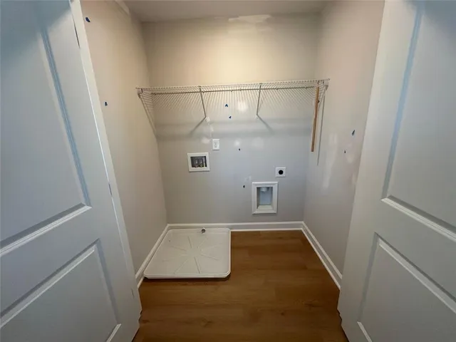 a view of an empty room with wooden floor and a kitchen