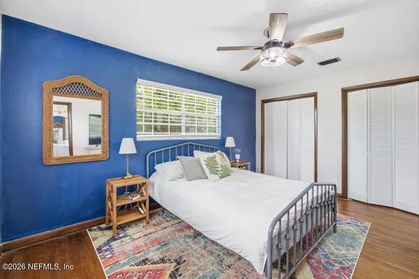 a bedroom with a bed a dresser and potted plant
