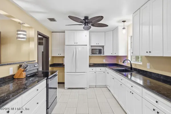 a kitchen with white cabinets and appliances