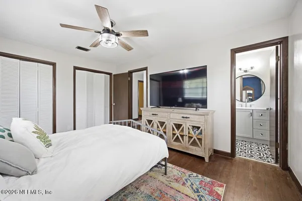 a bedroom with a large bed a flat tv screen and a chandelier