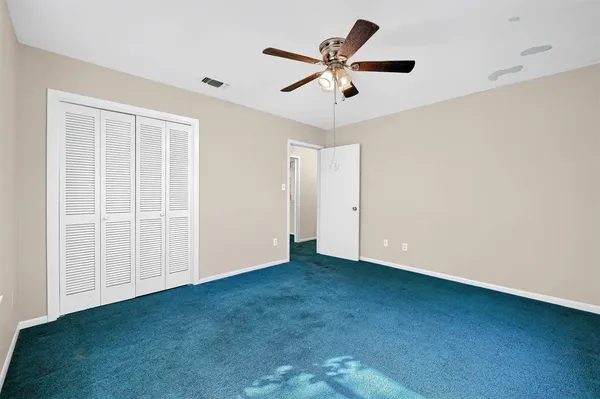 an empty room with a ceiling fan and window