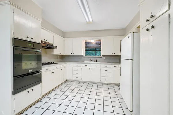 a kitchen with white cabinets and refrigerator