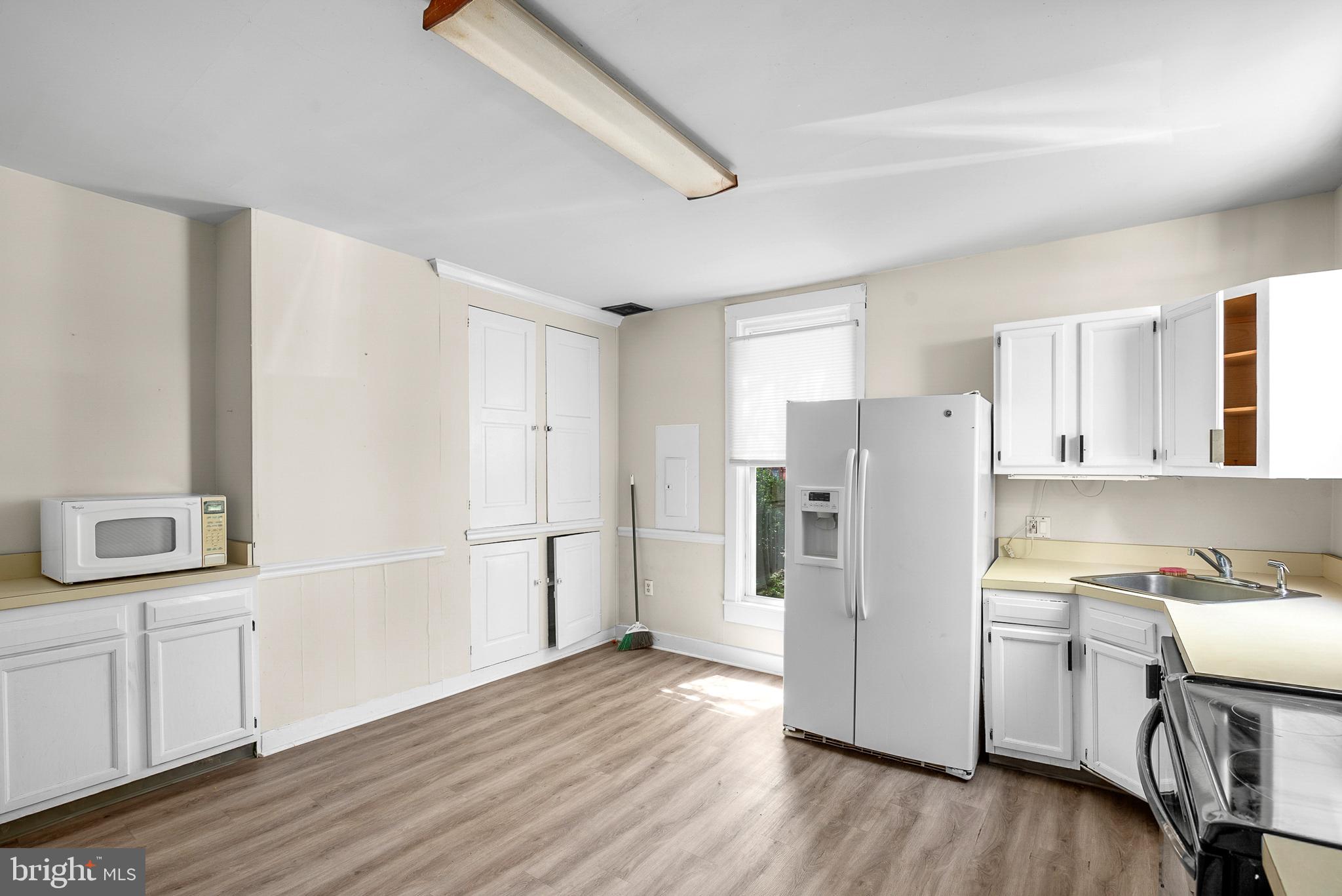 156 Main Street Preston, MD 21655 - Photo 2 of 18 a kitchen with a refrigerator a sink and dishwasher with wooden floor