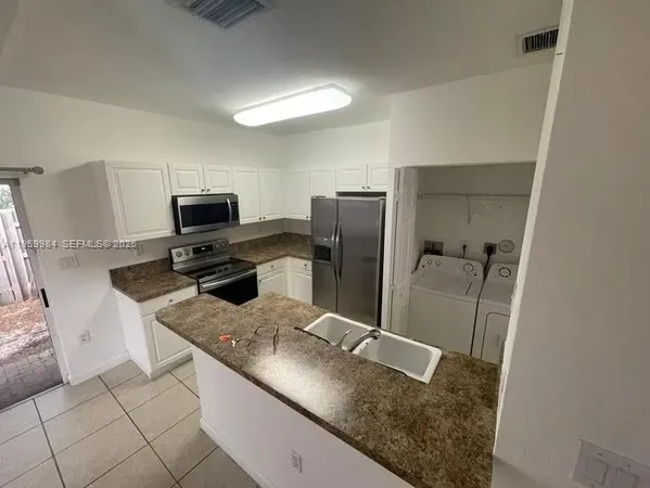 a kitchen with stainless steel appliances granite countertop a refrigerator and a sink