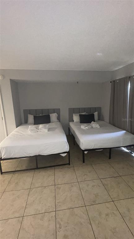 6165 Carrier Drive, Unit 1114 Orlando, FL 32819 - Photo 9 of 31 a bedroom with a bed and a table