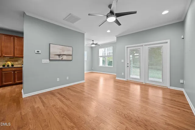 a view of an empty room with window and wooden floor