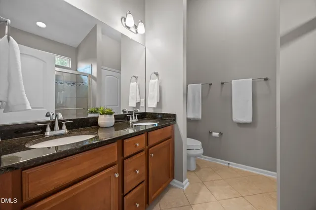 a bathroom with a granite countertop toilet sink and mirror