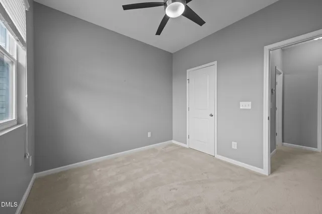 an empty room with ceiling fan and window