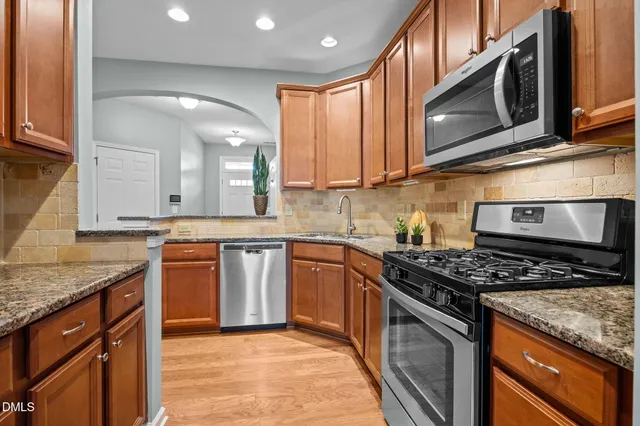 a kitchen with stainless steel appliances granite countertop a stove a sink and a microwave