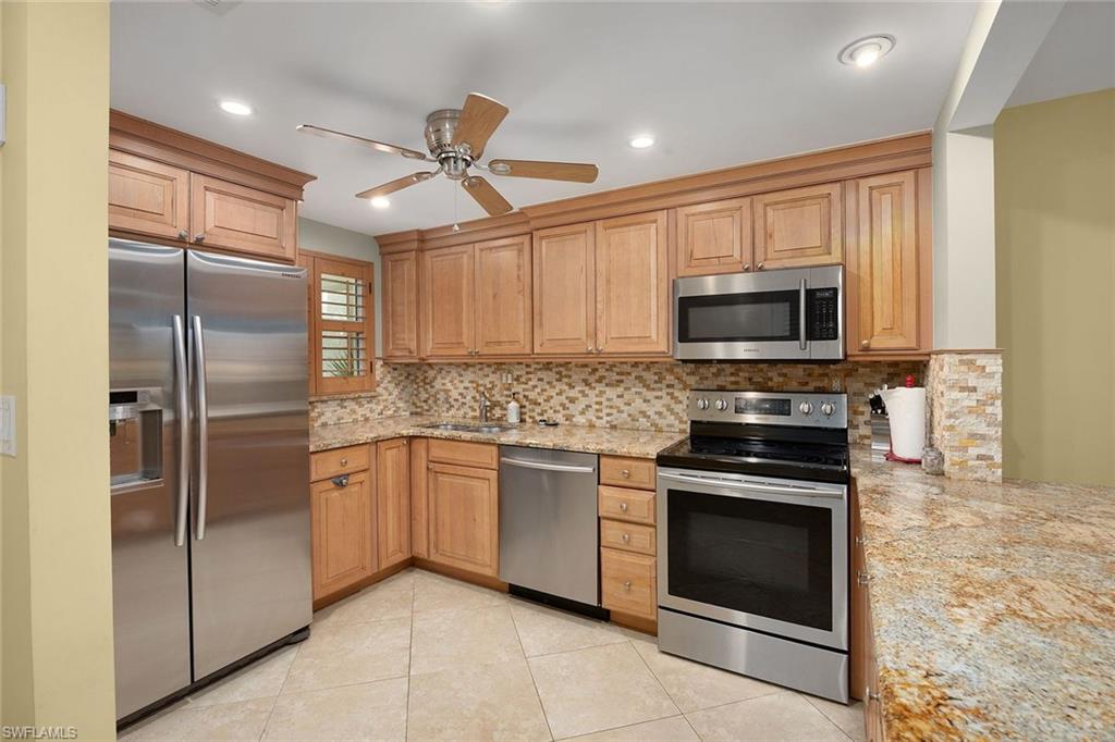 41 High Point Circle South, Unit 107 Naples, FL 34103 - Photo 8 of 29 a kitchen with stainless steel appliances granite countertop a refrigerator a stove top oven a sink and dishwasher