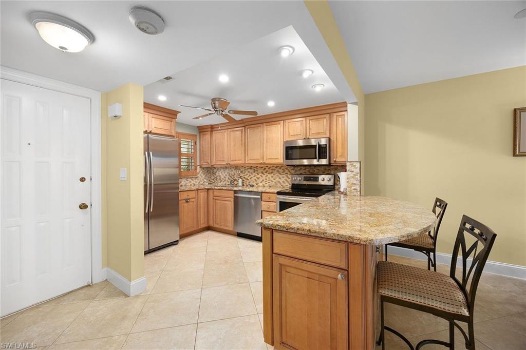 41 High Point Circle South, Unit 107 Naples, FL 34103 - Photo 9 of 29 a kitchen with a table chairs refrigerator and microwave