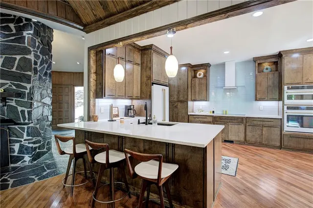 a kitchen with stainless steel appliances granite countertop a refrigerator a stove a sink a dining table and chairs with wooden floor