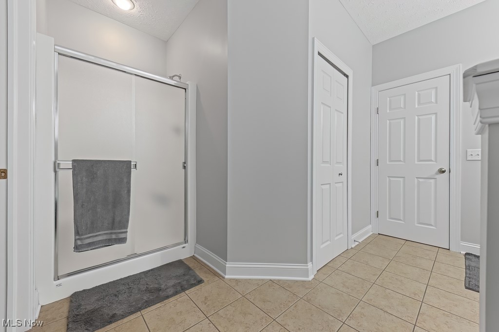 369 Eldridge Road Aurora, OH 44202 - Photo 18 of 50 Full bath with a textured ceiling, a shower stall, and tile patterned floors