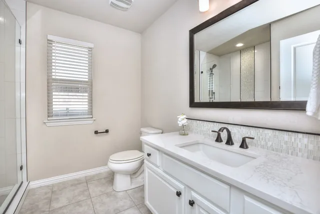 a bathroom with a granite countertop sink a toilet and a mirror