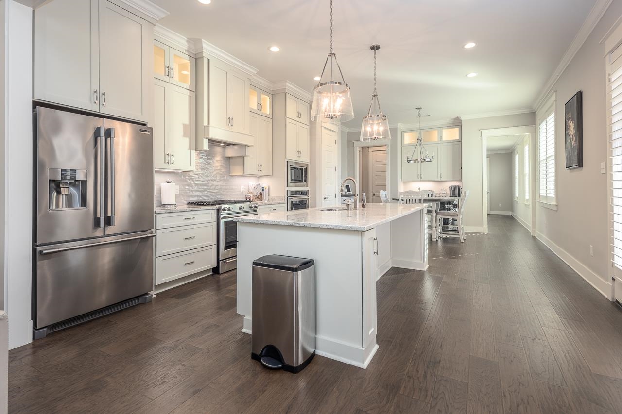 458 South Shea Road Collierville, TN 38017 - Photo 11 of 27 Kitchen with light stone counters, an island with sink, appliances with stainless steel finishes, dark wood-type flooring, and decorative light fixtures