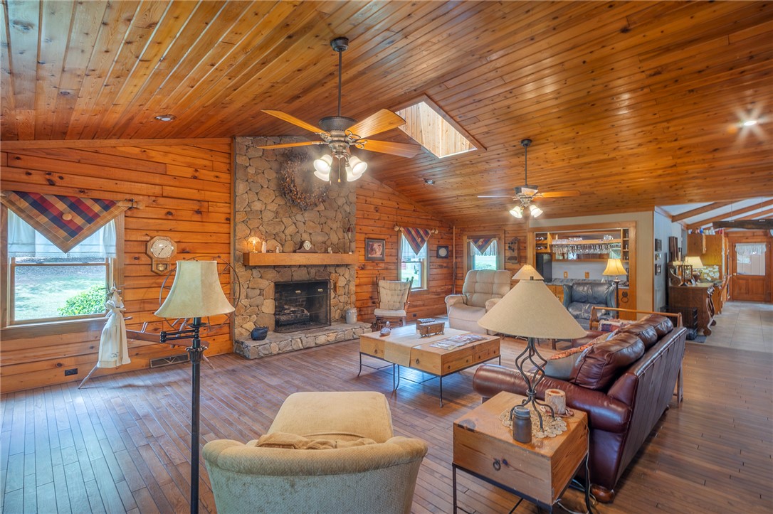 911 State Rd S-4-203 Belton, SC 29627 - Photo 19 of 49 A spacious lodge-style living room boasts natural wood walls and ceiling, centered around a grand stone fireplace.