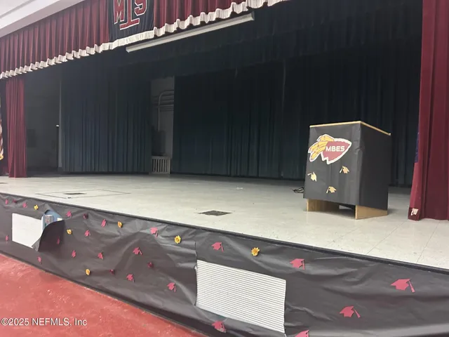 a dining hall with stainless steel appliances granite countertop a barbecue grill and couches with wooden floor