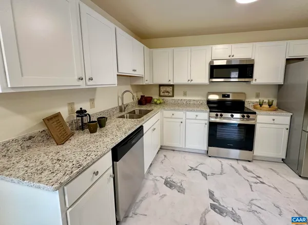 a kitchen with granite countertop a sink a stove top oven and cabinets