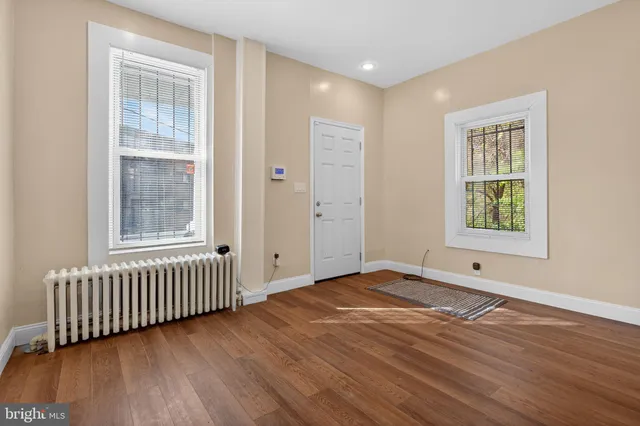 an empty room with wooden floor and windows