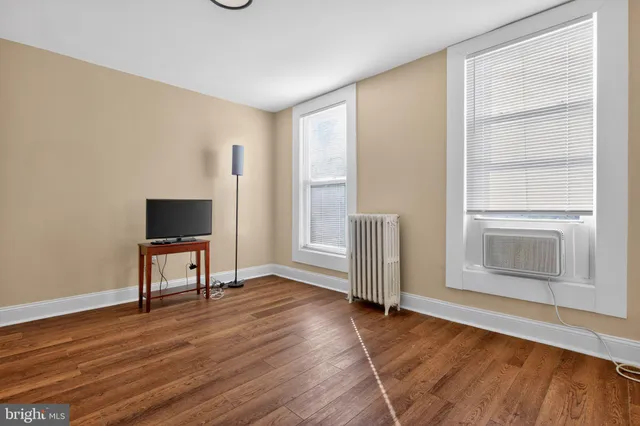 an empty room with wooden floor cabinet and windows