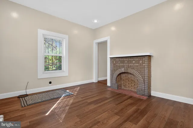 a view of empty room with wooden floor and fireplace