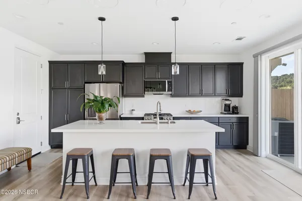 a kitchen with a stove a sink and living room view