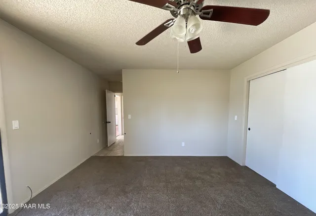 an empty room with a chandelier fan and windows