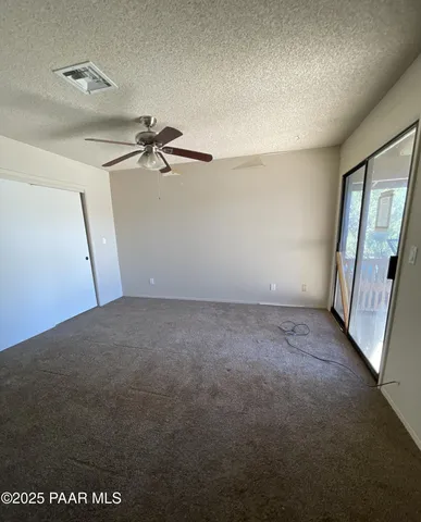 an empty room with a ceiling fan and window