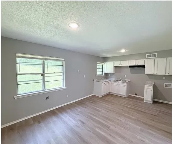 a living room with stainless steel appliances kitchen island wooden floors and white walls
