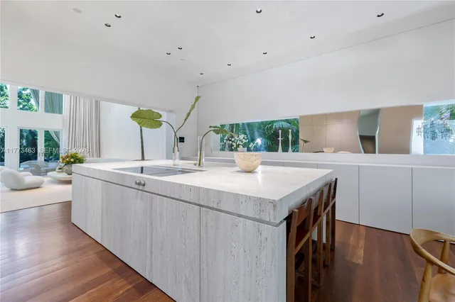 a kitchen with stainless steel appliances kitchen island a wooden floor and a sink