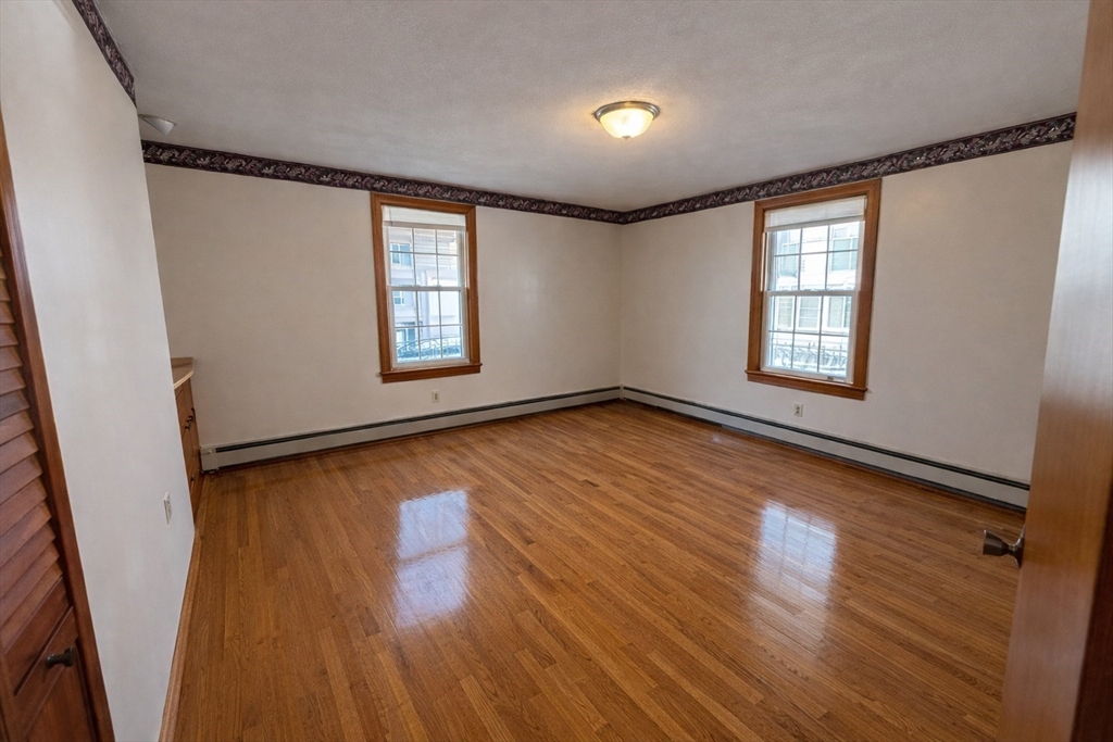 198 Washington Street, Unit 1 Somerville, MA 02143 - Photo 8 of 15 an empty room with wooden floor and windows