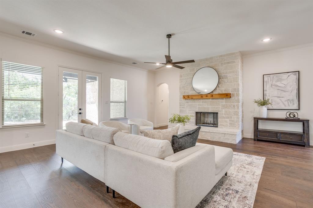 608 Tay Tay Way Springtown, TX 76082 - Photo 8 of 40 Stone-clad fireplace with wood mantel, dark wood-finish flooring, recessed lighting, ceiling fan, and French doors