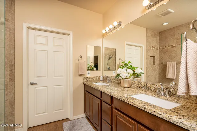 a bathroom with a granite countertop double vanity sink and mirror