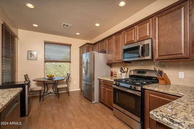 a kitchen with stainless steel appliances granite countertop a stove a sink dishwasher a microwave oven with cabinets and wooden floor